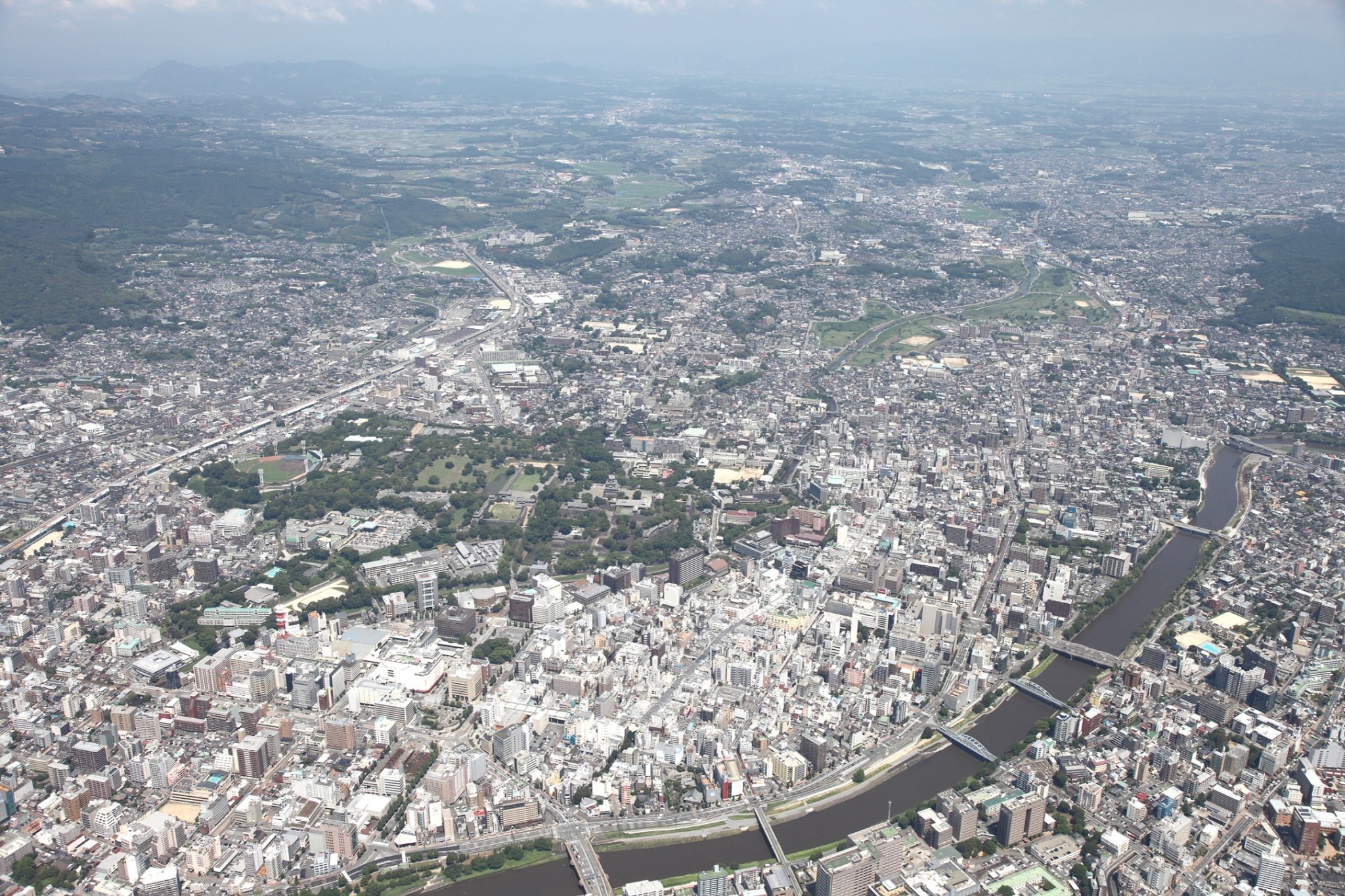 熊本城や白川と周辺の市街地を上空から望む写真